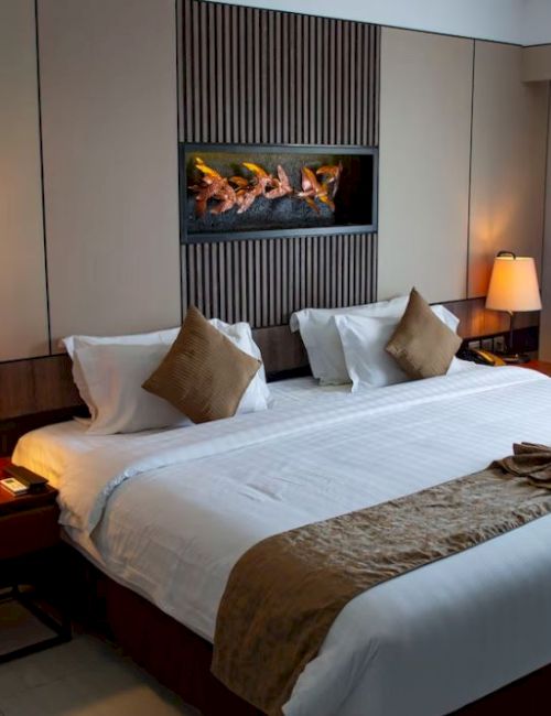 A modern hotel room with a large bed, two bedside tables with lamps, and a wall-mounted decorative element above the bed, ending the sentence.