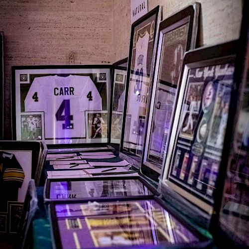 The image shows a display of sports memorabilia, including framed pictures and signed jerseys, with one prominently featuring the name 