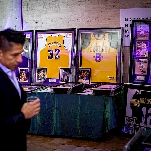 A man is in front of a display featuring framed sports jerseys, including a yellow 