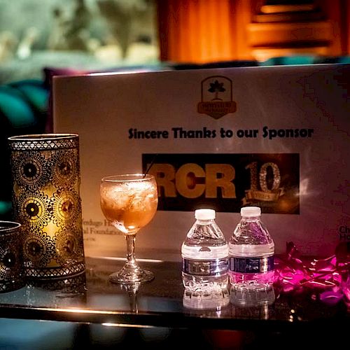 The image shows a table with candles, drinks, and a sign reading 