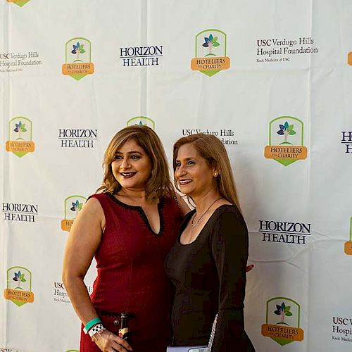 Two people posing in front of a backdrop with logos of Horizon Health, USC Verdugo Hills Hospital Foundation, and Glendale Arts.