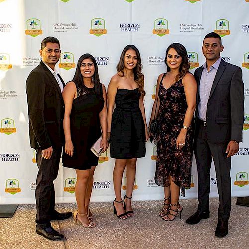 Five people are dressed in formal attire, posing in front of a backdrop featuring the Morton Kiwanis Bike Hospital Foundation and sponsor logos.