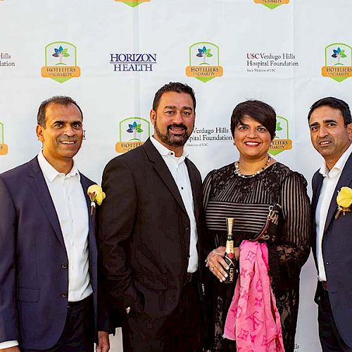 A group of four people posing in front of a step and repeat banner with branding for Horizon Health and USC Verdugo Hills Hospital Foundation.