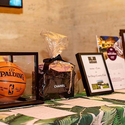 The image shows a table with a framed basketball, a Chanel gift package, framed papers, and a signed sports jersey with the number 22 on the back.