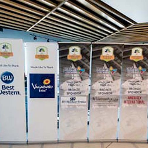 The image shows several banners with sponsor logos, including Best Western and Vagabond Inn, standing in a row at an event.