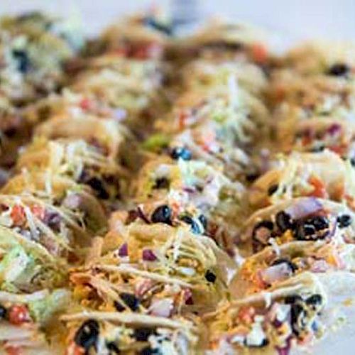 The image shows a plate filled with small, colorful tacos that contain vegetable fillings and shredded cheese.