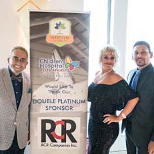 Three people pose next to a banner thanking RCR Companies Inc. as a Double Platinum Sponsor for Children’s Hospital Los Angeles.